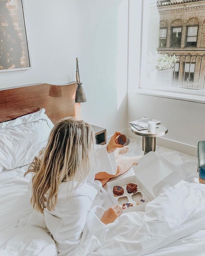A woman eating cupcakes in her hotel room